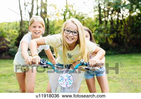 Stock Photograph - Girls cycling in garden. Fotosearch