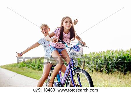 Girls cycling on country road View Large Photo Image Stock Image - Girls cycling on country road. Fotosearch