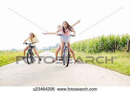 Stock Photograph - Girls cycling on country road. Fotosearch