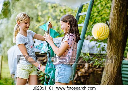 Stock Image - Girls decorating garden for summer party. Fotosearch