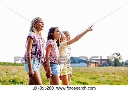 Stock Image - Girls enjoying view in field, Flanders, Belgium. Fotosearch