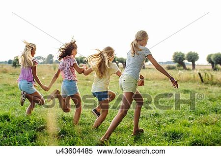 Stock Photography - Girls holding hands, running in line, on field, Flanders, Belgium. Fotosearch