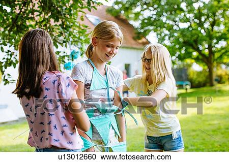 Stock Image - Girls wrapping friend up in bunting. Fotosearch
