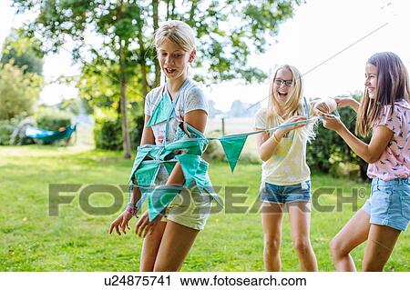 Stock Image - Girls wrapping friend up in bunting. Fotosearch
