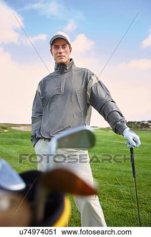 Golfer holding gold club, hand in pocket, looking at camera View Large Photo Image Stock Image - Golfer holding gold club, hand in pocket, looking at camera. Fotosearch
