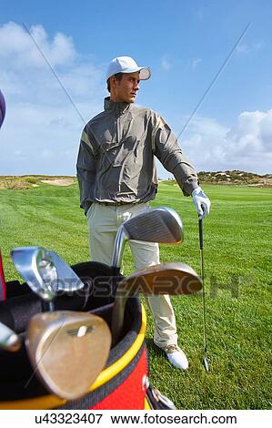Golfer holding gold club, hand in pocket, looking away View Large Photo Image Stock Photo - Golfer holding gold club, hand in pocket, looking away. Fotosearch