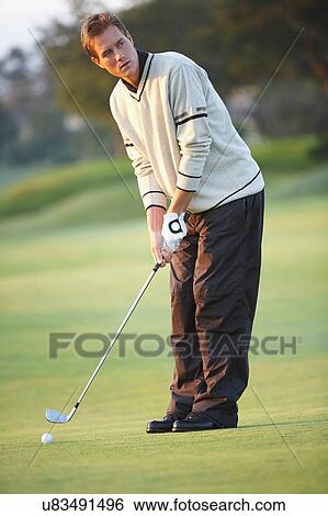 Golfer holding golf club preparing to take gold swing, looking away View Large Photo Image Stock Photograph - Golfer holding golf club preparing to take gold swing, looking away. Fotosearch