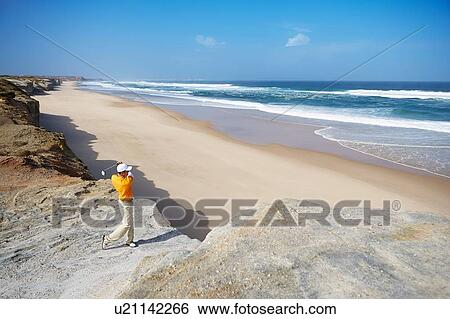 Golfer standing on cliff overlooking beach taking golf swing View Large Photo Image Stock Photograph - Golfer standing on cliff overlooking beach taking golf swing. Fotosearch