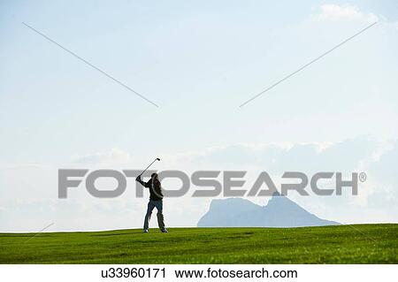 Golfer taking golf swing in front of mountain range View Large Photo Image Stock Image - Golfer taking golf swing in front of mountain range. Fotosearch