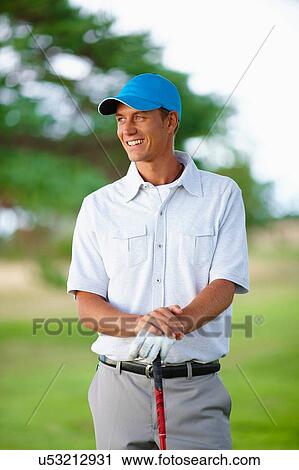 Golfer wearing golf glove and baseball cap holding golf club looking away smiling View Large Photo Image Stock Image - Golfer wearing golf glove and baseball cap holding golf club looking away smiling. Fotosearch