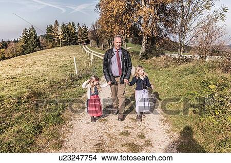Grandfather strolling on dirt track with two granddaughters, Achenkirch, Austria View Large Photo Image Picture - Grandfather strolling on dirt track with two granddaughters, Achenkirch, Austria. Fotosearch