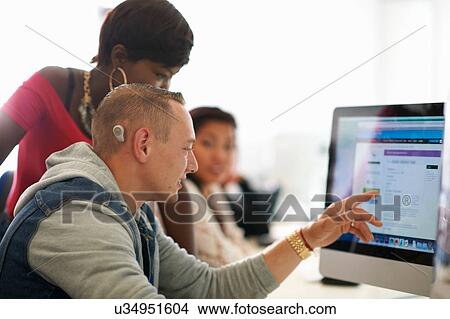 Group of students pointing at desktop computer in classroom View Large Photo Image Picture - Group of students pointing at desktop computer in classroom. Fotosearch