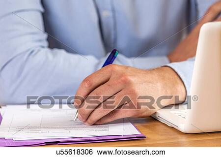 Stock Photograph - Hand of woman doing paperwork at desk. Fotosearch