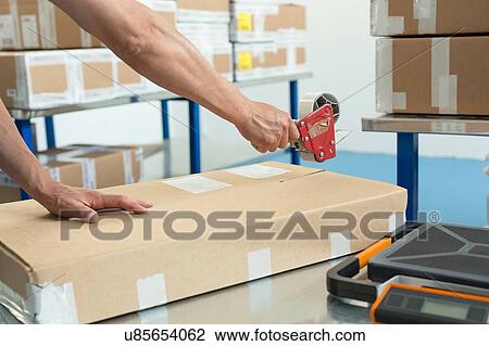 Hands of warehouse worker taping parcel in distribution warehouse View Large Photo Image Stock Image - Hands of warehouse worker taping parcel in distribution warehouse. Fotosearch