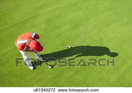 Stock Image - High view of golfer and shadow putting. Fotosearch