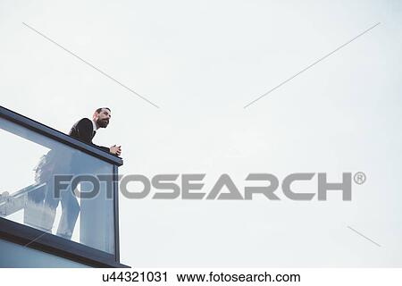Low angle view of businessman looking out from office balcony View Large Photo Image Stock Image - Low angle view of businessman looking out from office balcony. Fotosearch