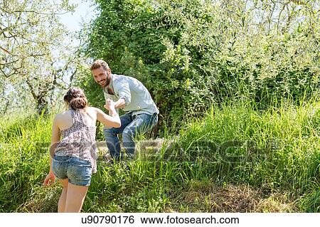 Low angle view of young man helping young woman up hill View Large Photo Image Stock Photograph - Low angle view of young man helping young woman up hill. Fotosearch