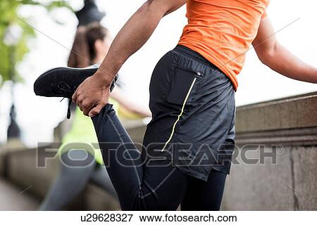 Male and female city runners stretching legs View Large Photo Image Stock Photo - Male and female city runners stretching legs. Fotosearch