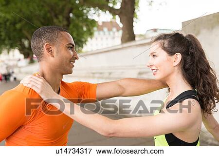 Male and female city runners warming up with hands on each others shoulders View Large Photo Image Stock Photo - Male and female city runners warming up with hands on each others shoulders. Fotosearch