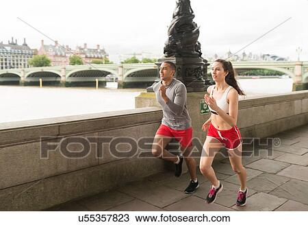 Stock Image - Male and female runners running on Southbank, London, UK. Fotosearch