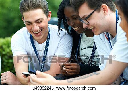 Male and female students on college campus reading smartphone message View Large Photo Image Stock Photography - Male and female students on college campus reading smartphone message. Fotosearch