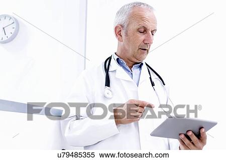Stock Photography - Male doctor looking at digital tablet. Fotosearch