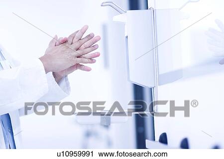 Stock Image - Male doctor using hand santizer. Fotosearch