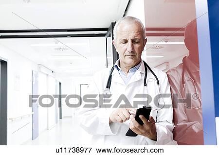 Stock Photo - Male doctor using smartphone. Fotosearch