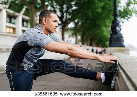 Stock Photography - Male runner doing warm up preparation on riverside. Fotosearch
