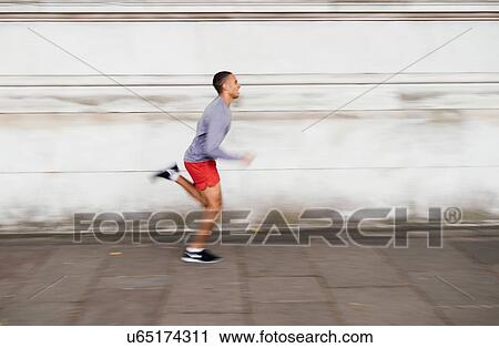 Male runner speeding along sidewalk View Large Photo Image Stock Image - Male runner speeding along sidewalk. Fotosearch