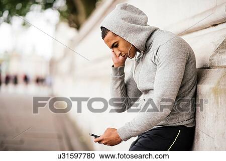 Male runner wearing grey hoody reading smartphone texts View Large Photo Image Stock Image - Male runner wearing grey hoody reading smartphone texts. Fotosearch