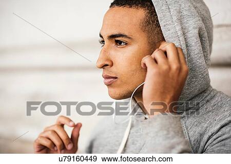 Male runner wearing grey hoody listening to earphone music View Large Photo Image Stock Photo - Male runner wearing grey hoody listening to earphone music. Fotosearch