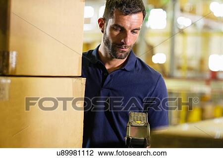 Stock Image - Male warehouse worker using barcode scanner in distribution warehouse. Fotosearch