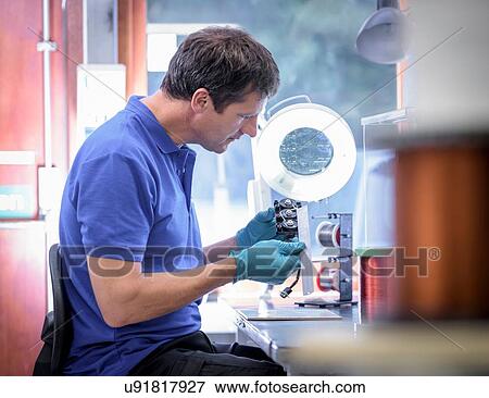 Stock Photo - Male worker assembling electromagnetic coils in electronics factory. Fotosearch