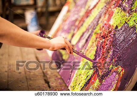 Stock Image - Man painting on canvas in studio. Fotosearch