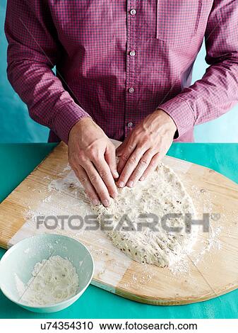 Stock Image - Man preparing unkneaded bread recipe step 2, shaping bread dough. Fotosearch