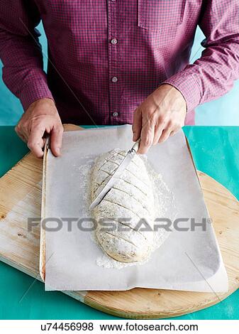Stock Photo - Man preparing unkneaded bread recipe step 3, marking bread dough. Fotosearch