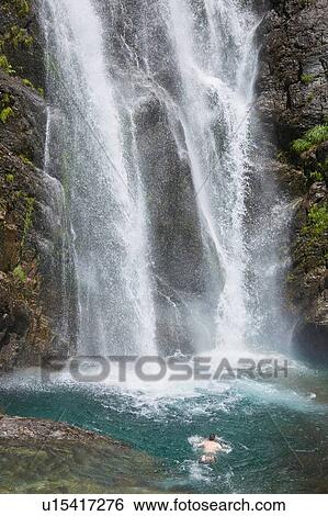 Stock Photograph - Man swimming near waterfall, Saut Deth Pish, Valle de Aran, Spain. Fotosearch
