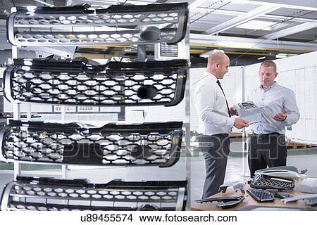 Picture - Managers inspecting automotive parts in spray paint factory. Fotosearch