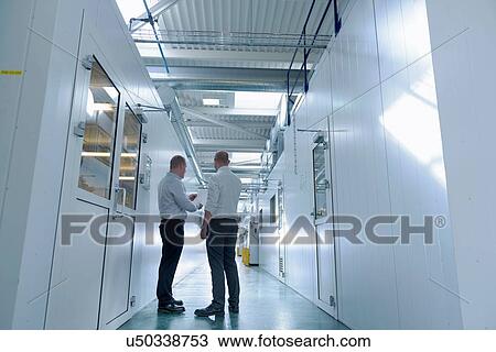 Stock Image - Managers inspecting robotic spray booths in automotive parts spray paint factory. Fotosearch