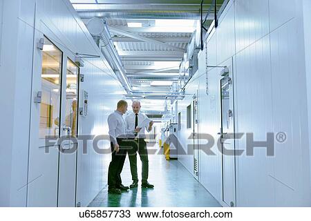 Stock Image - Managers inspecting robotic spray booths in automotive parts spray paint factory. Fotosearch