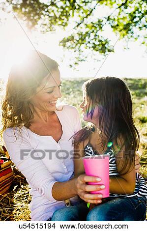 Mature woman and daughter drinking from paper cups at park picnic View Large Photo Image Picture - Mature woman and daughter drinking from paper cups at park picnic. Fotosearch