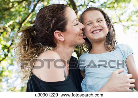 Stock Photo - Mature woman and daughter giggling in park. Fotosearch