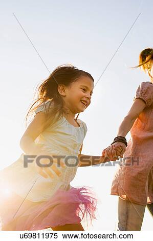Stock Photography - Mature woman and daughter holding hands and running in park. Fotosearch