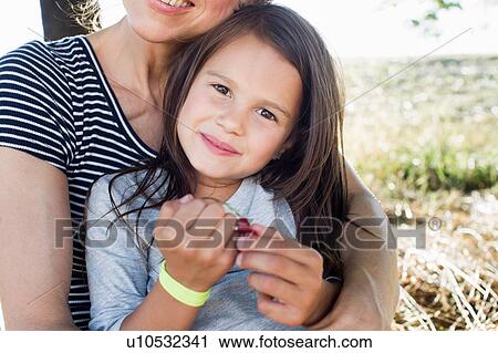Stock Image - Mature woman and daughter in park eating redcurrants. Fotosearch