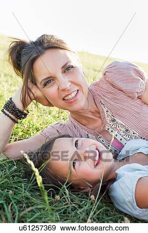 Mature woman and daughter reclining in park View Large Photo Image Stock Photo - Mature woman and daughter reclining in park. Fotosearch