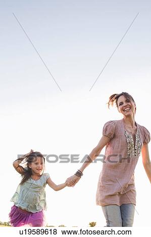 Stock Photo - Mature woman and daughter running in park. Fotosearch