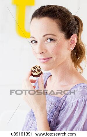 Mature woman holding sweet baked product looking at camera smiling View Large Photo Image Stock Image - Mature woman holding sweet baked product looking at camera smiling. Fotosearch