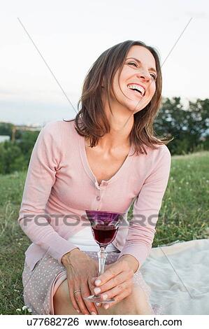Mature woman laughing whilst drinking red wine in park View Large Photo Image Stock Photograph - Mature woman laughing whilst drinking red wine in park. Fotosearch