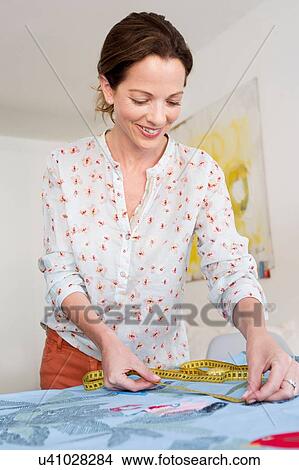Mature woman measuring colourful fabric, looking down smiling View Large Photo Image Picture - Mature woman measuring colourful fabric, looking down smiling. Fotosearch
